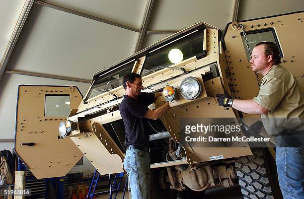 Civilian contractors uparmor heavy equipment vehicles January 14, 2005 at Camp Anaconda, Iraq. The production of add on armor is shifting from light...
