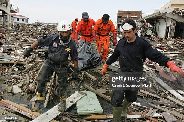Members of Mexican and German search and rescue teams retrieve a body amongst the rubble of destroyed homes January 14, 2005 in Banda Aceh,...