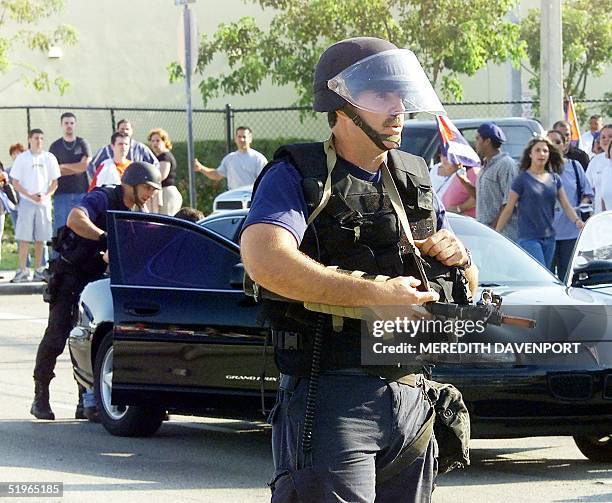 Miami police officers wearing riot gear clear the streets of protestors near the home where Cuban shipwreck survivor Elian Gonzalez had been staying...