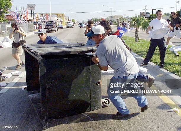 Protestors overturn a dumpster near the Miami home where Cuban shipwreck survivor Elian Gonzales had been staying with relatives in Miami 22 April...