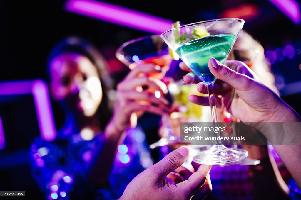 Jungen Freunden anstoßen mit Getränke während der Nacht-club Partei
