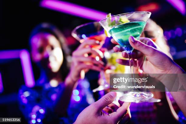 jóvenes amigos brindis con bebidas de cortesía durante la fiesta del club de noche - clubs fotografías e imágenes de stock