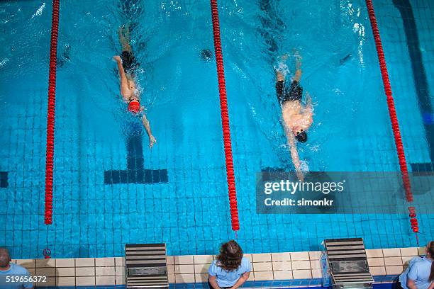 männliche schwimmer im swimmingpool - schwimmwettkampf stock-fotos und bilder