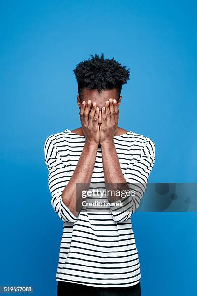 pain, afro american guy hiding his face in hand - awkward stock pictures, royalty-free photos & images