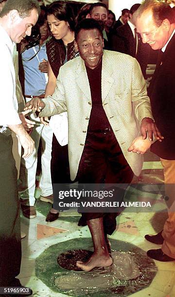 Edson Arantes do Nascimento, known as Pele, steps in fresh cement to leave his mark on the path of fame at the Maracana stage 16 June 2000 in Rio de...