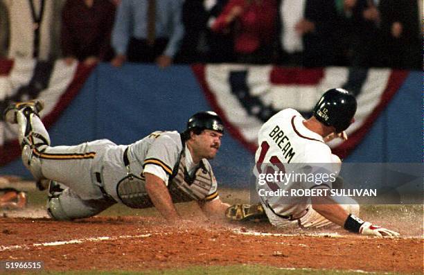 The Atlanta Braves Sid Bream slides across the plate to win the National League Championship Series as the Pittsburgh Pirates catcher Mike LaValliere...