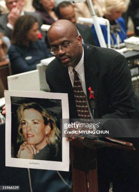 Prosecutor Christopher Darden holds a smiling portrait of murder victim Nicole Brown Simpson to contrast it with photos of a battered Nicole shown to...
