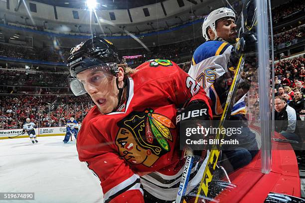 Dale Weise of the Chicago Blackhawks and Ryan Reaves of the St. Louis Blues get physical by the boards in the first period of the NHL game at the...