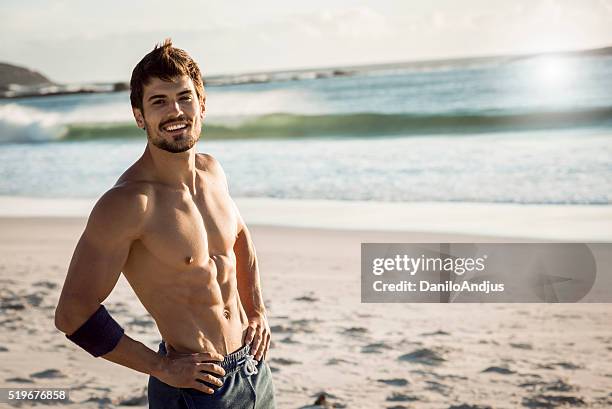 souriant s'adapter homme se détendre après l'entraînement. - men abs beach photos et images de collection
