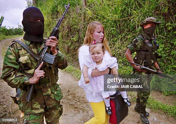 Members of the Colombian Autodefense Units of Colombia paramilitary group escort teacher Maribel Lopez and her one-year-old daughter as they are...