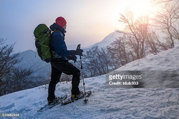 hombre disfruta de la puesta de sol mientras caminatas con raquetas para nieve un través de un bosque - snowshoeing fotografías e imágenes de stock