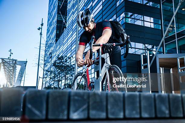 commuter parking his bicycle outside the office entrance - bicycle parking station stock pictures, royalty-free photos & images