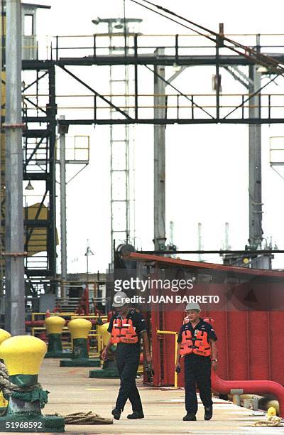 Workers of the Venezuelan oil company walk by the wharf of oil supply plant located in Maracaibo, 550 km from Caracas, Venezuela, 13 October 2000....