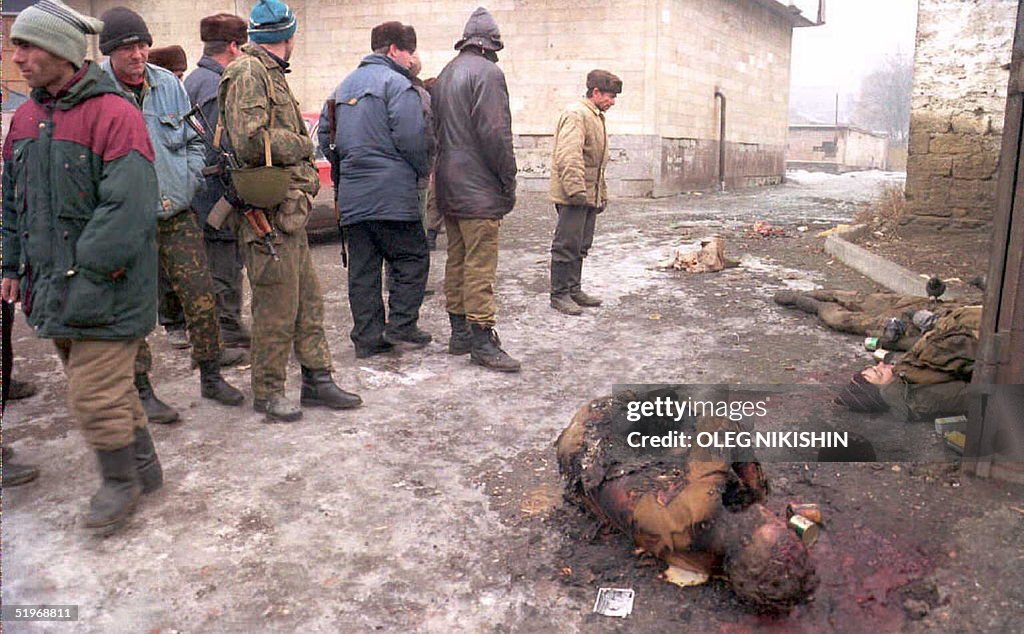 A group of Chechen volunteers walk past the bodies