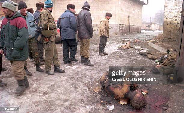 Group of Chechen volunteers walk past the bodies of two Russian soldiers who were killed during the last assault on the capital Grozny 01 January...