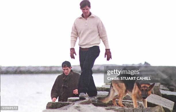 John F. Kennedy Jr. , William Kennedy Smith and J.F.K. Jr.'s dog Sampson walk along a breakwater on the family compound in Hyannisport 23 January....