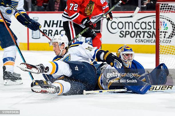 Jay Bouwmeester of the St. Louis Blues slides into goalie Brian Elliott in the first period of the NHL game against the Chicago Blackhawks at the...