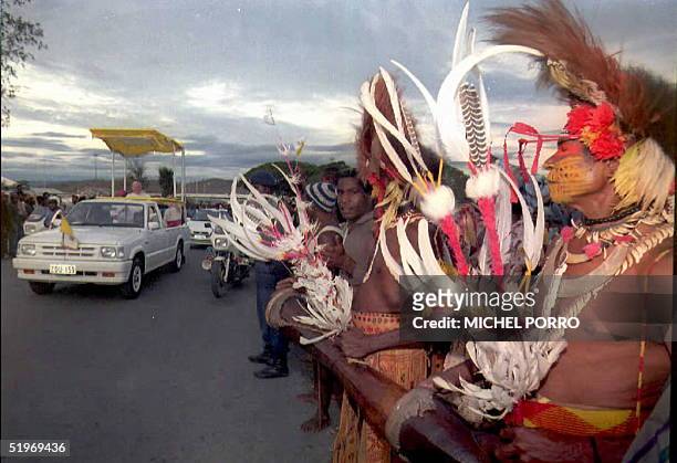 Native Papua New Guinea tribesmen line up on a street in Port Moresby to catch a glimpse of Pope John Paul II as he rides from the airport in his...