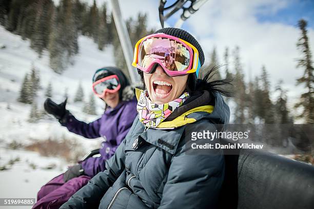 girls laughing and having fun on a chair lift. - sport d'hiver photos et images de collection