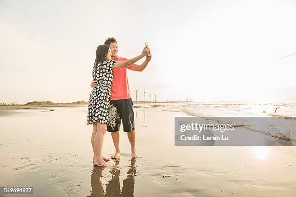 young couple taking selfie with phone on beach. - taiwan beach stock pictures, royalty-free photos & images