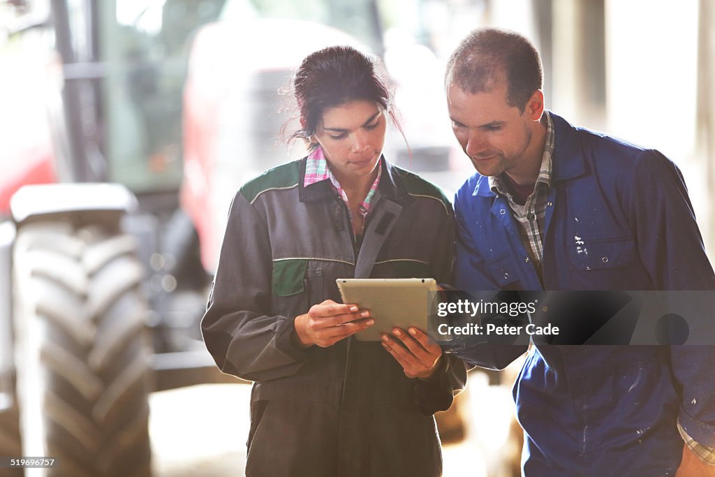 Famers couple on farm  looking at a tablet.