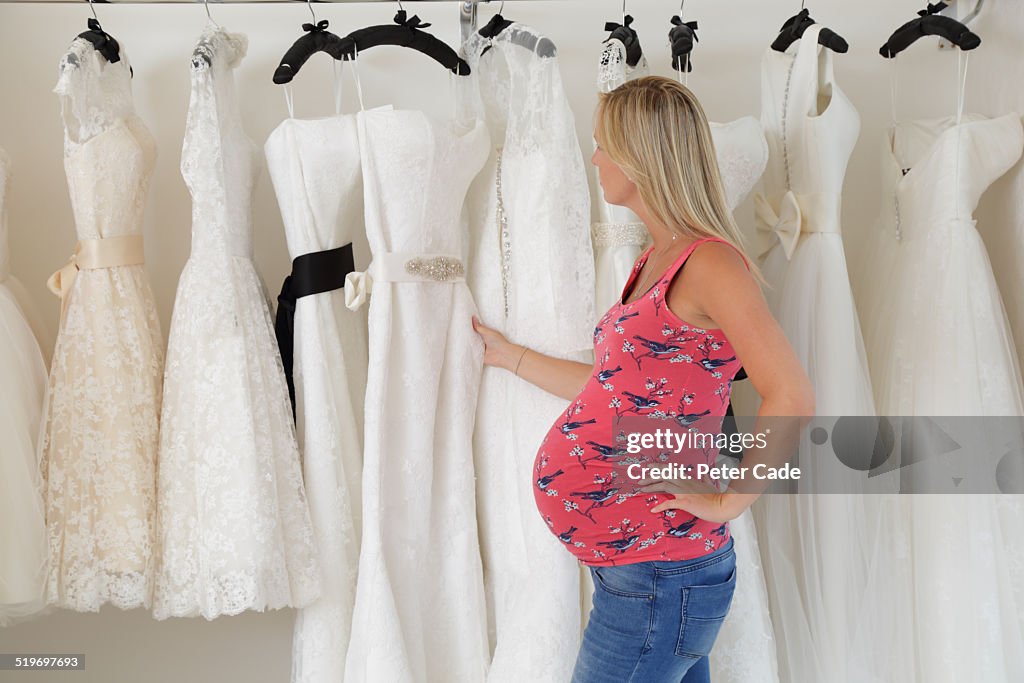 Pregnant lady looking at wedding dresses.