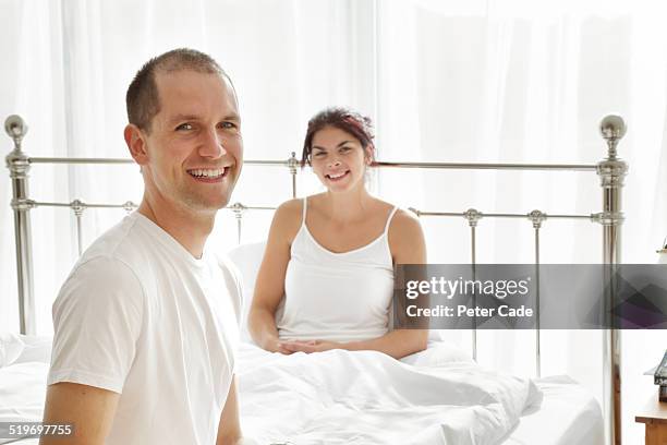 young couple in bed smiling at the camera . - receding stock pictures, royalty-free photos & images