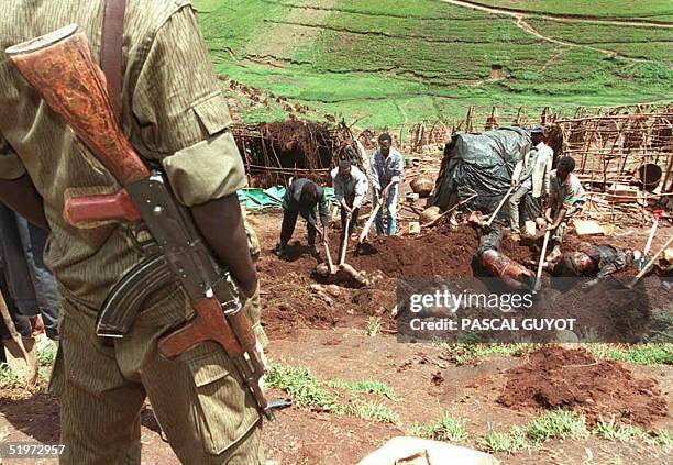 Rwandan soldier stands guard as bodies are exhumed from a mass grave at the Kibeho refugee camp 27 April to count the dead following the massacre of...