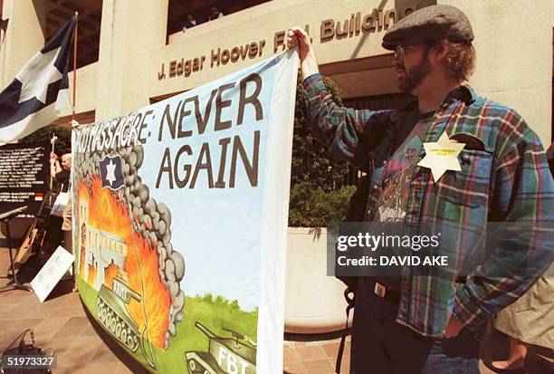 Andrew Williams, of Washington, DC holds up a sign depicting the scene at the Brach Davidian compound in Waco, Texas during a rally at the FBI...