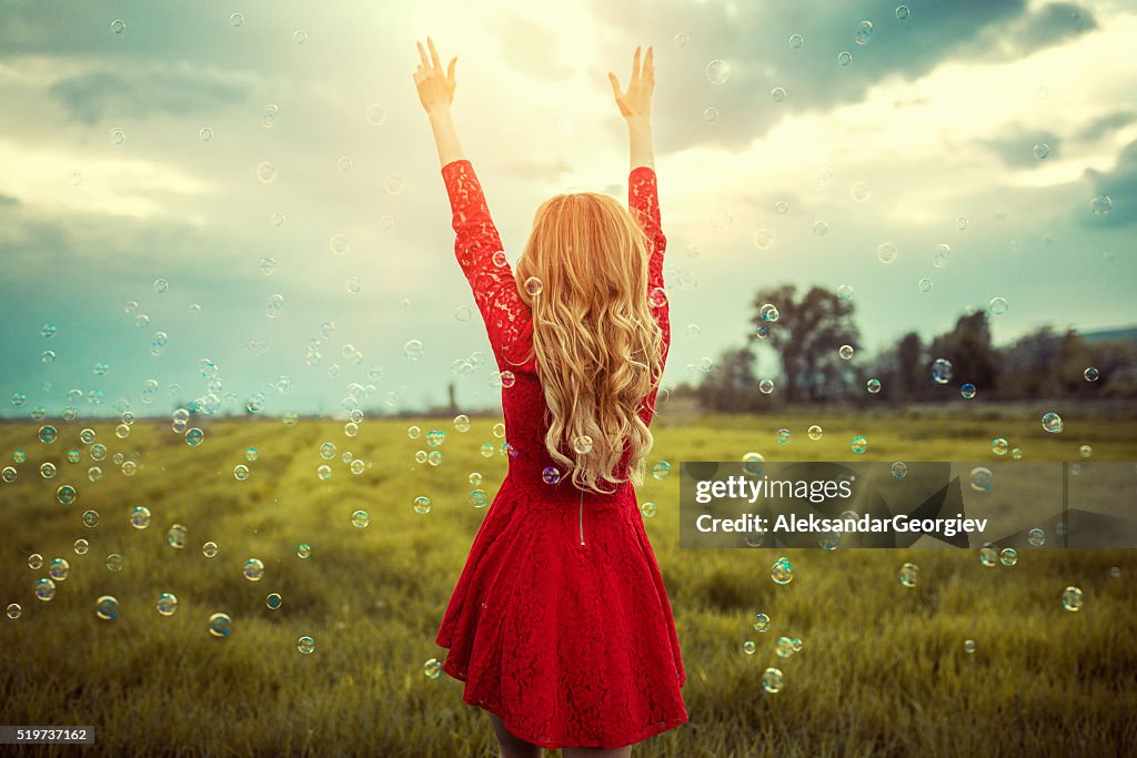 Blonde Girl Enjoying Nature with Spread Arms Surrounded with Bubbles