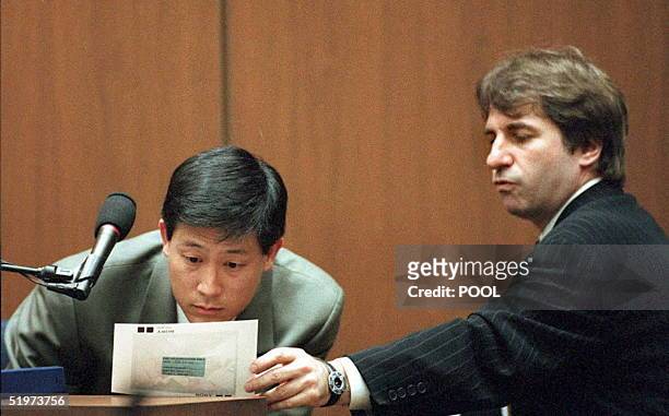Defense DNA expert Barry Scheck holds a photograph of a bloody glove as criminalist Dennis Fung examines it during cross examination 05 April in the...