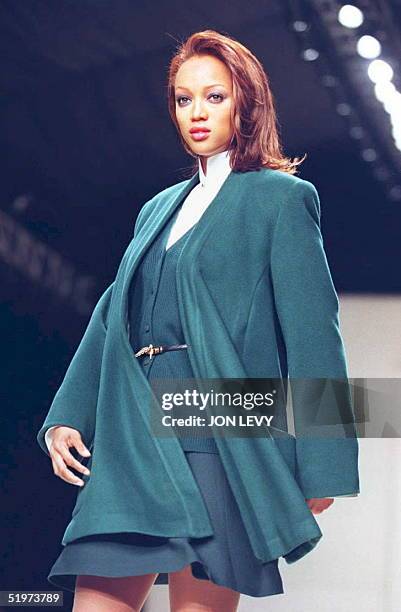 Model Tyra Banks presents a malachite wool wrap coat with matching wool ribbed cardigan and flip skirt over a white cotton trapunto collar shirt in...