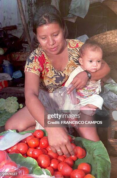Ana Estela empaca tomates para vender en una calle de San Salvador,El Salvador,07 Mayo mientras cuida de su hijo Carlos de ocho meses. Segun un...