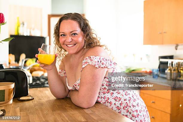 oversize woman drinking orange juice at home - hot housewives stock pictures, royalty-free photos & images