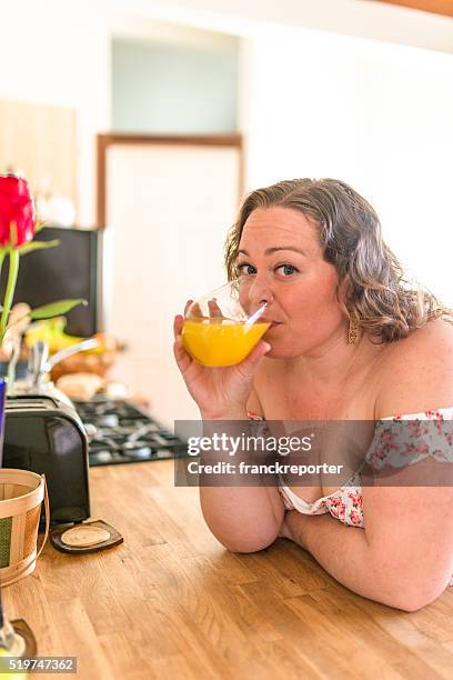 oversize woman drinking orange juice at home - hot housewives stock pictures, royalty-free photos & images