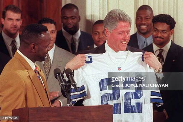 President Bill Clinton holds a Dallas Cowboys jersey presented to him by running back Emmitt Smith bearing Smith's number during a ceremony 13...