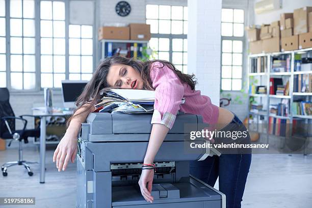 tired assistant sleeping on a copy machine - fotokopieerapparaat stockfoto's en -beelden