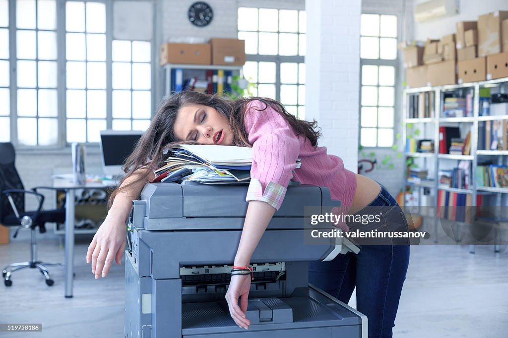 Tired assistant sleeping on a copy machine