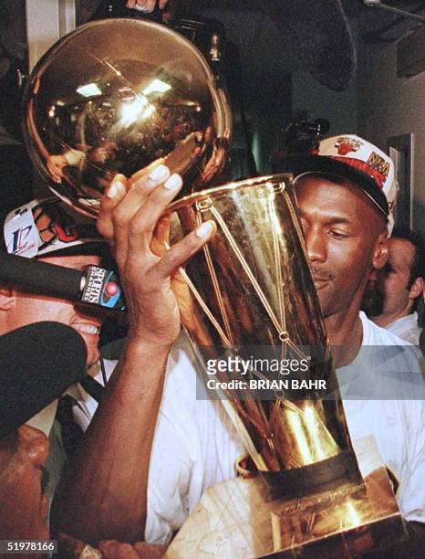Michael Jordan of the Chicago Bulls holds the Larry O'Brian trophy outside the Bulls locker room after game six of the NBA Finals at the United...