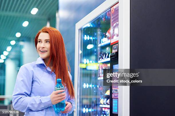 smiling while picking up my water - verkoopautomaat stockfoto's en -beelden