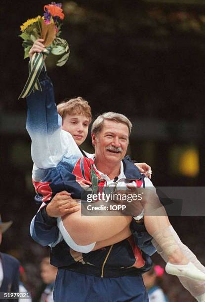 Olympic artistic gymnastics' coach Bela Karolyi carries injured gymnast Kerri Strug onto the podium after his team won the women's gold medal 23 July...