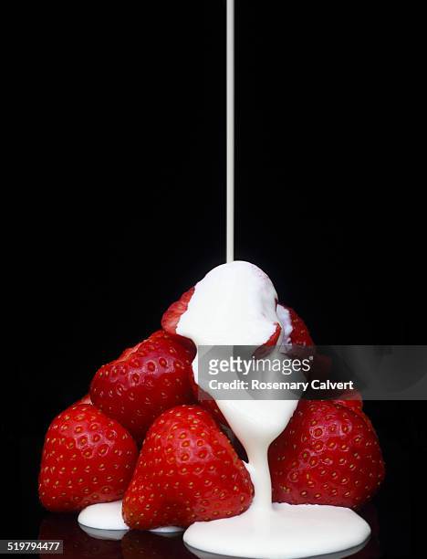 ripe strawberries running with fresh double cream - temptation stock-fotos und bilder