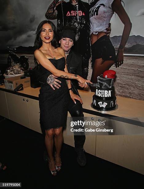 Model Nathalia Henao and her husband, guitarist Dj Ashba of Sixx:A.M., cut a cake during the grand opening of their Ashba Clothing Store at the...