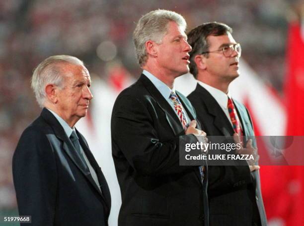 Chairman Juan Antonio Samaranch flanks US President Bill Clinton and ACOG President and CEO Billy Payne while they sing the US national anthem during...