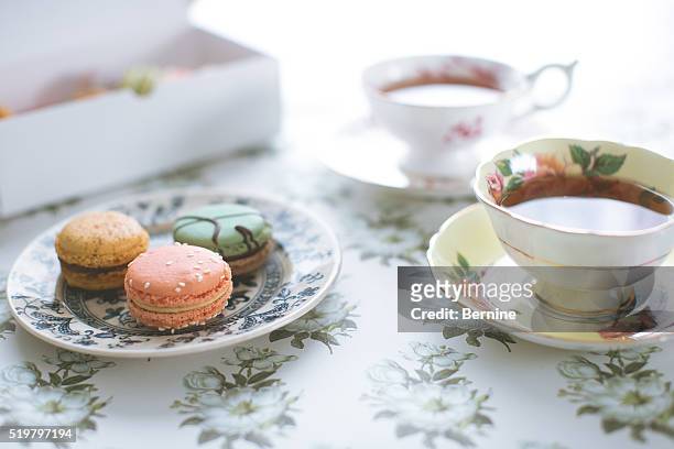 plate of macarons in front of tea cups - アフタヌーンティー ストックフォトと画像