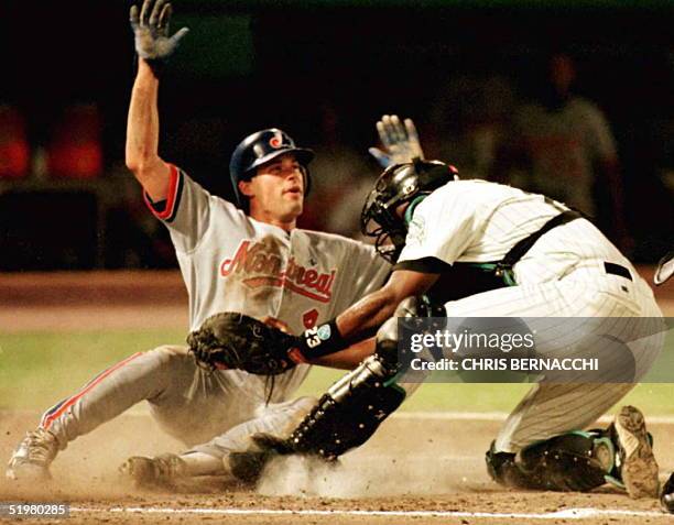 Florida Marlins catcher Charles Johnson tags out Monteal Expos shortstop Mark Grudzielanek at home plate 07 September during the third inning of...