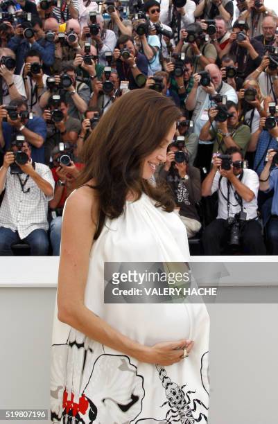 Actress Angelina Jolie craddles her baby bump during a photocall for US directors John Stevenson and Mark Osborne animated film 'Kung Fu Panda' at...