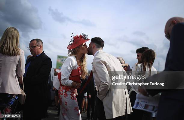 Two racegoers kiss as they enjoy the atmosphere of Ladies Day, the second day of the Aintree Grand National Festival meeting, on April 8, 2016 in...