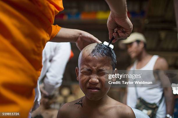 Kemachart grimaces as a monk shaves his head at Wat Supan Rangsri on April 05, 2016 in Mae Sariang, Thailand. Han and Kemachart are neighbors in...