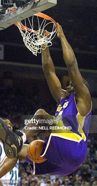 Los Angeles Laker center Shaquille O'Neal hangs on the rim after a dunk against the Charlotte Hornets in the first half at the Charlotte Coliseum in...